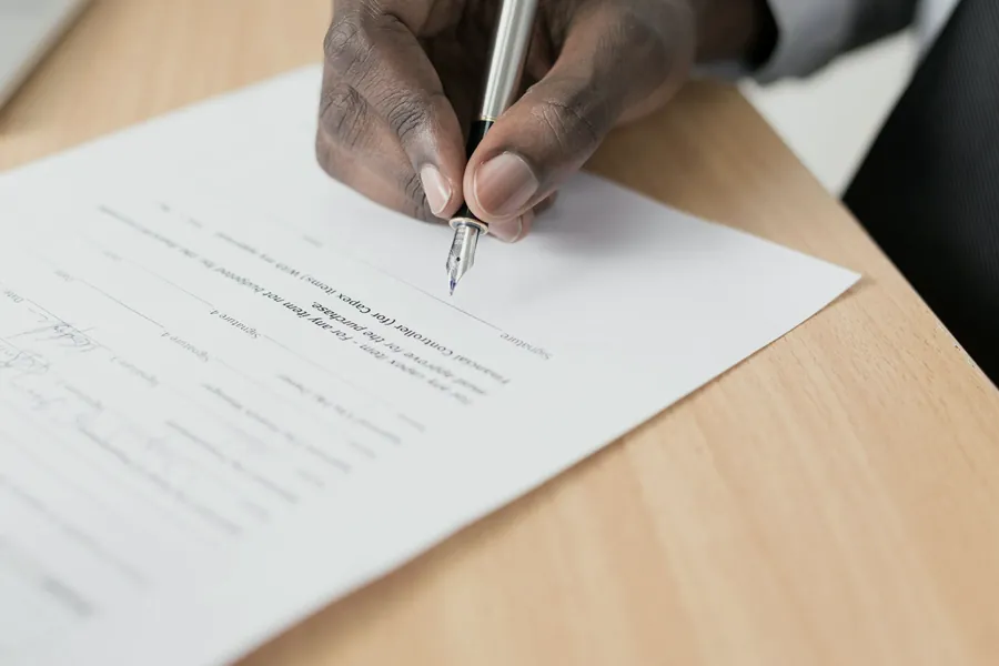 Mão assinando um contrato.